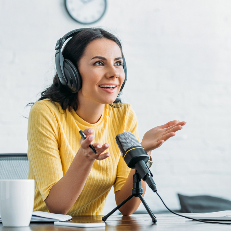 women at a desk talking into a microphone