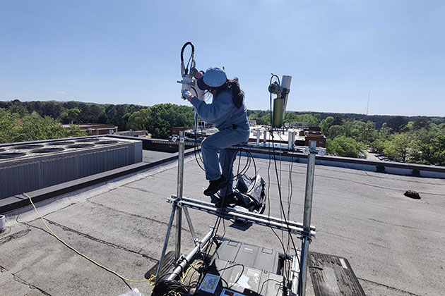 female researcher on a ladder working on a piece of equipment