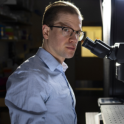 Researcher works beside a microscope in a laboratory.