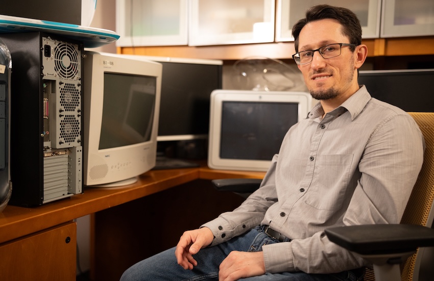 Zsolt Kira sitting in office chair surrounded by old computers