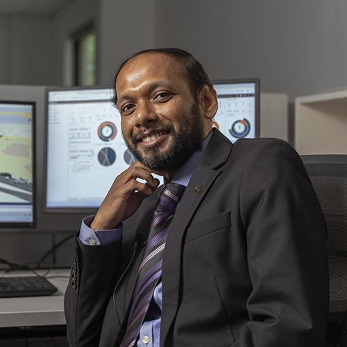 headshot of Angshuman Guin sitting in front of monitors with his hand on his chin