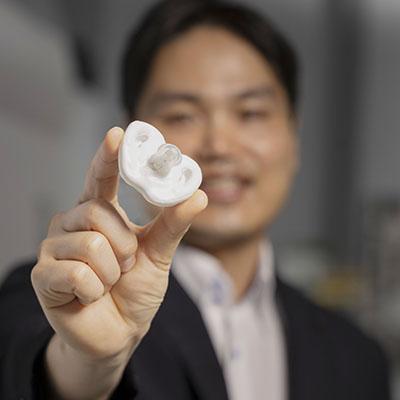 Hong Yeo holding a white pacifier under development at Georgia Tech