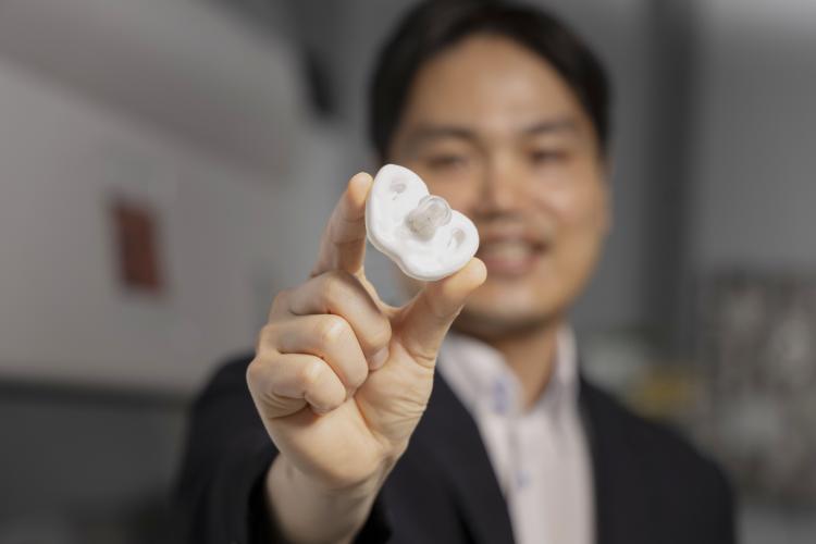 Hong Yeo holding a white pacifier under development at Georgia Tech
