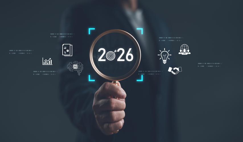 Businessman holding magnifying glass focusing on year 2026 with digital icons of innovation, AI, analytics, and global strategy. Concept of future planning, technology trends and vision. 