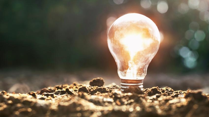 An Adobe stock conceptual image of a lighted bulb in the dirt illustrating new technology that draws energy from dirt.