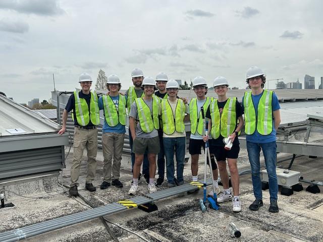Georgia Tech Beautification Day volunteers on the rooftop of CNES building, with the cleaned solar panels in the background