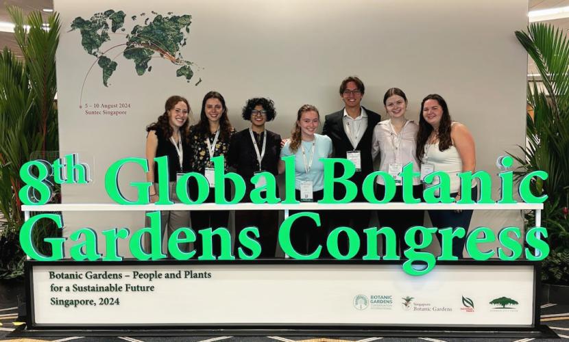 A group of Georgia Tech students gather for a group photo including a sign that says, "8th Global Botanic Gardens Congress."