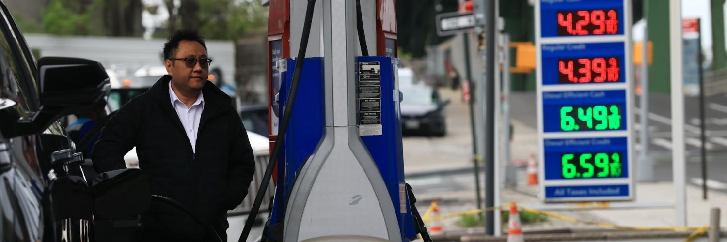 A person filling gas in his car with the gas prices shown in the foreground