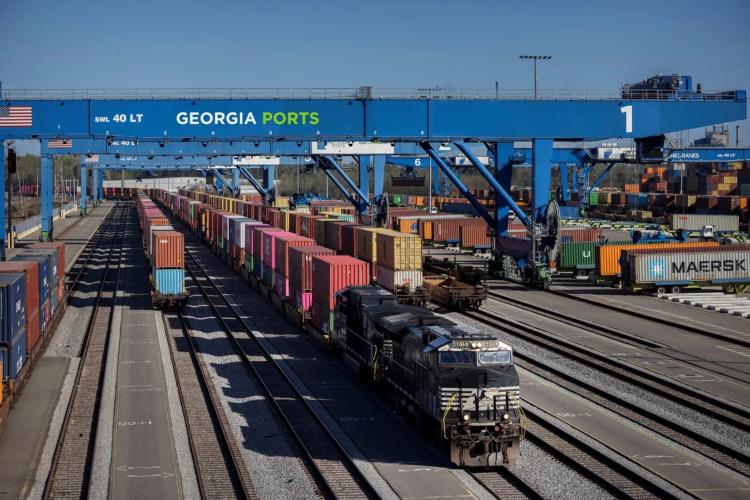 Railroad yard serving the Georgia Ports Authority with more than 6 railroad lanes with one engine towing a long line of intermodal containers.