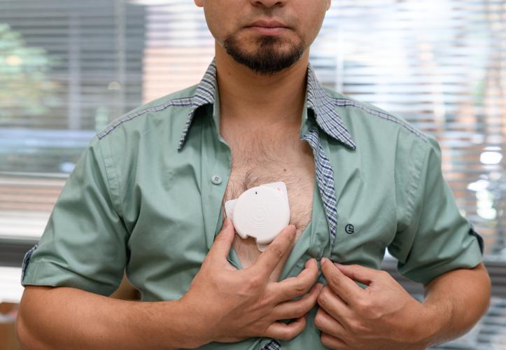 man baring chest an holding a patch against his skin