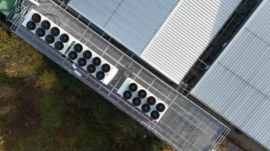 Aerial view of a datacenter with air conditioner compressor fans on the roof of the building