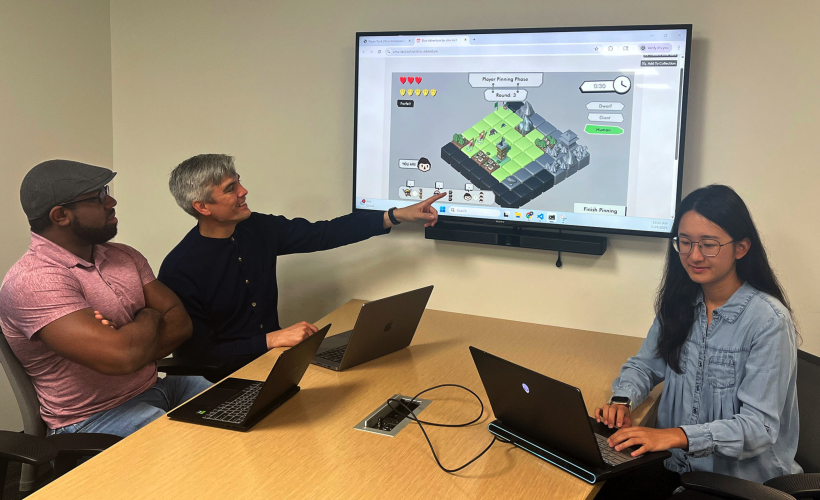 Pictured: Interactive PhD students Glen Smith (far left) and Qiao Zhang (far right) working with Assistant Professor Christopher MacLellan on the Dice Adventure game. 