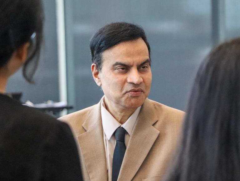 A man in a suit speaking with two students. 