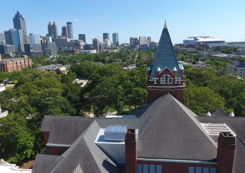 Aerial view of Georgia Tech’s historic campus in Atlanta, with the Tech Tower prominently in the foreground and the Atlanta skyline visible in the background under a clear blue sky.