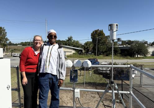 IPaT researcher Jill Gambill is pictured with David Shabaka, Harambee House, in Savannah. Behind them are three newly designed air monitors (white plastic leaf enclosures) waiting for installation in different locations.