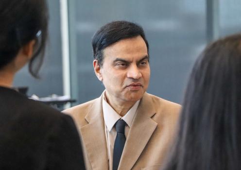 A man in a suit speaking with two students. 