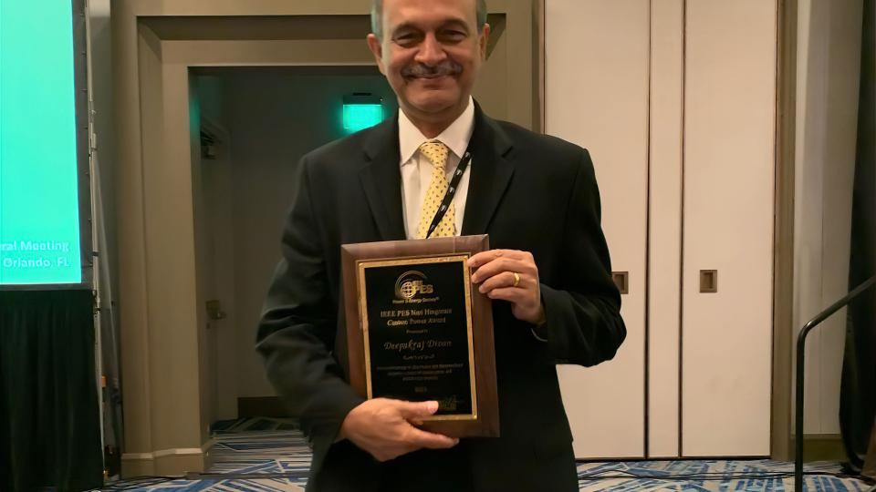 Photo of ECE Professor Deepakraj Divan holding the 2023 Nari Hingorani Custom Power Award plaque.