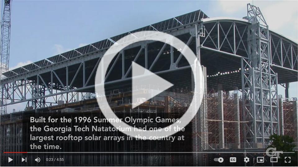 Image capture from the BBISS 30th Anniversary Video of the Georgia Tech Olympic Natatorium with a play button overlay.