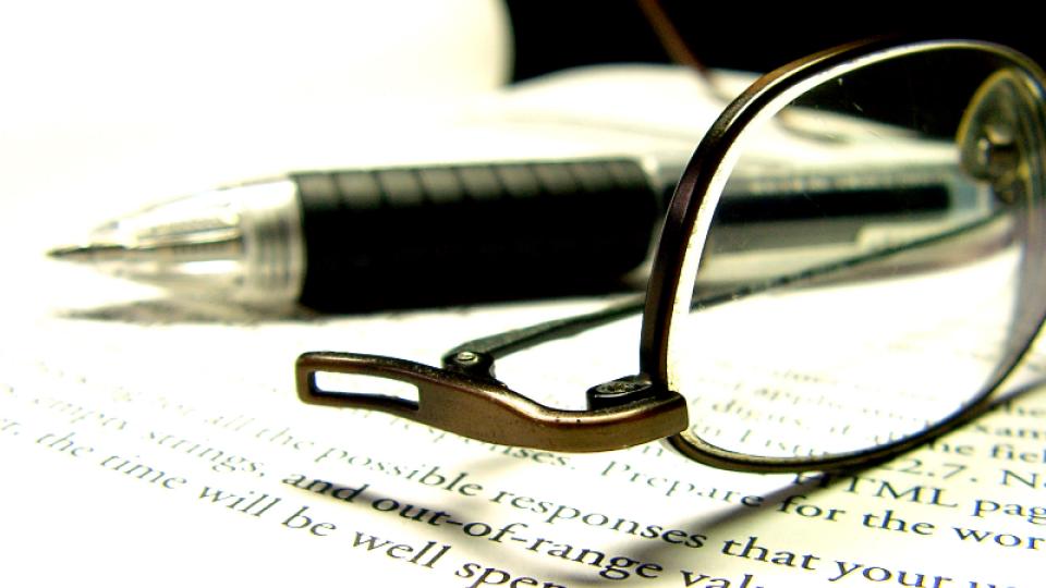 a pair of glasses and a pencil lay on a paper