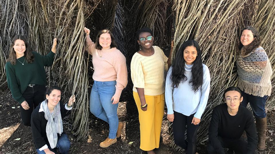 Group photo of the first class of BBISS GRA Scholars in front of the EcoCommons Patrick Dougherty Sculpture installation. They are Katherine Duchesneau, Ioanna Maria Spyrou, Meaghan McSorley, Bettina Arkhurst, Udita Ringania, Yilun 'Elon' Zha, and Marjorie Hall.