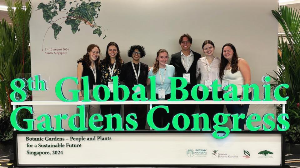 A group of Georgia Tech students gather for a group photo including a sign that says, "8th Global Botanic Gardens Congress."