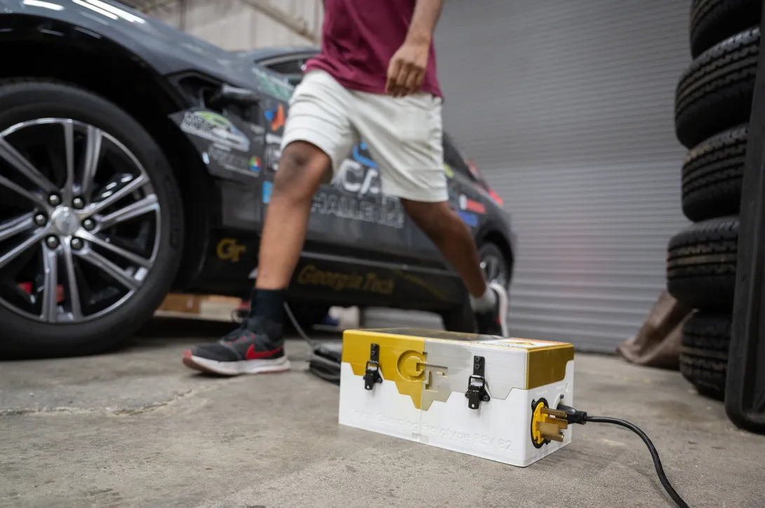 A gold and white charger box in front of a car