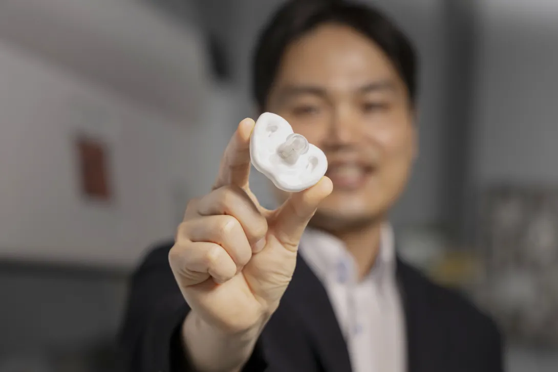 Hong Yeo holding a white pacifier under development at Georgia Tech