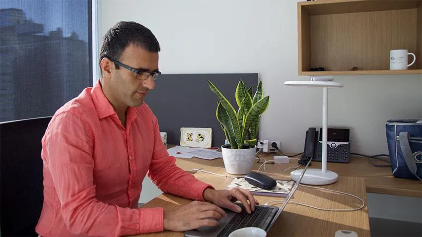 Man in salmon colored shirt working at computer