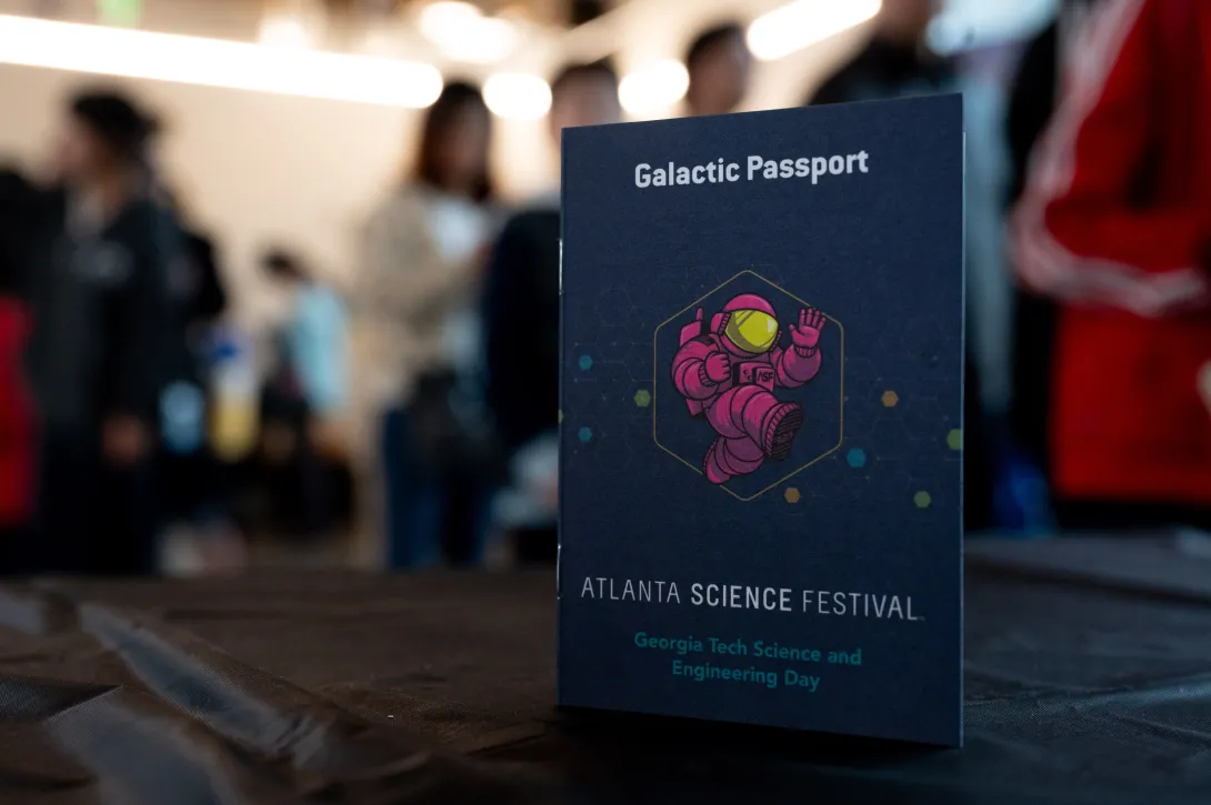 <p><span>The Atlanta Science Festival Galactic Passport that visitors used to navigate their explorations around Georgia Tech's campus (Credit: Joya Chapman)</span></p> A blue booklet with an illustration of a pink astronaut