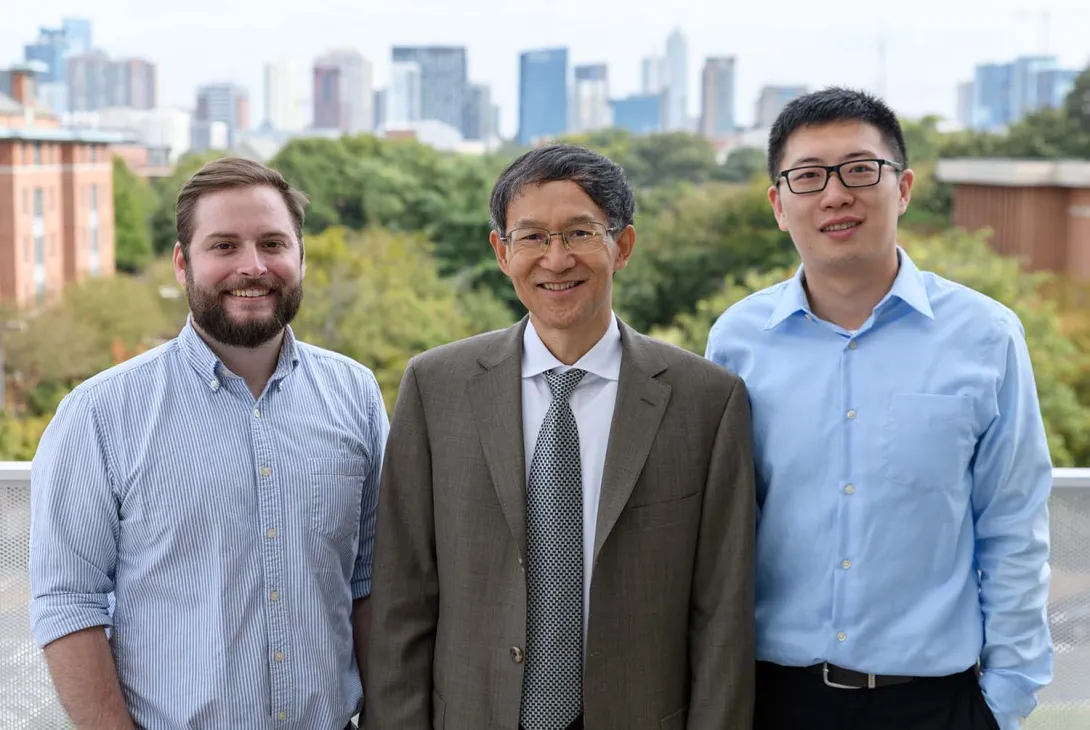 Three Georgia Tech researchers in front of the Atlanta skyline.