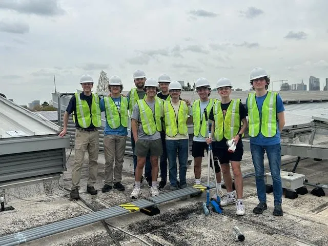Georgia Tech Beautification Day volunteers on the rooftop of CNES building, with the cleaned solar panels in the background