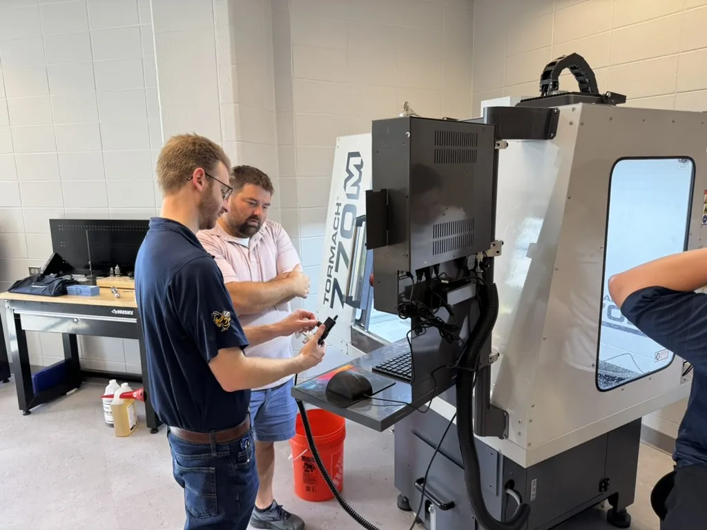 Kyle Saleeby (left) works side-by-side with a teacher to set up precision milling equipment, a key part of the AMP Program’s hands-on curriculum.