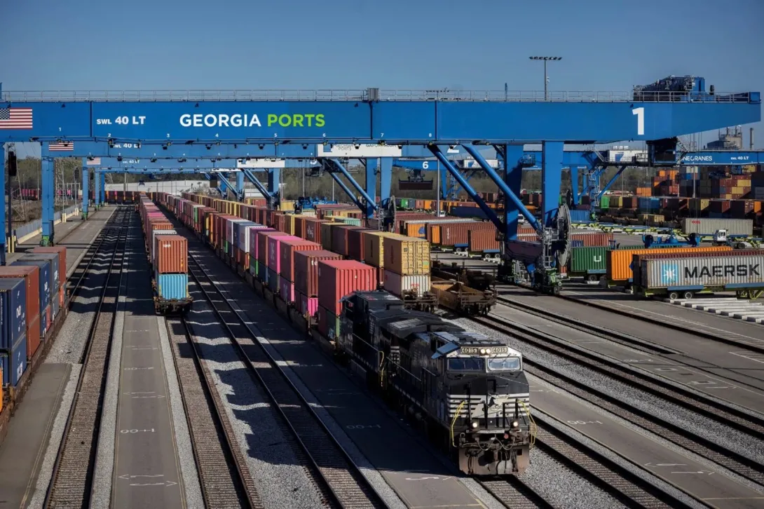 Railroad yard serving the Georgia Ports Authority with more than 6 railroad lanes with one engine towing a long line of intermodal containers.