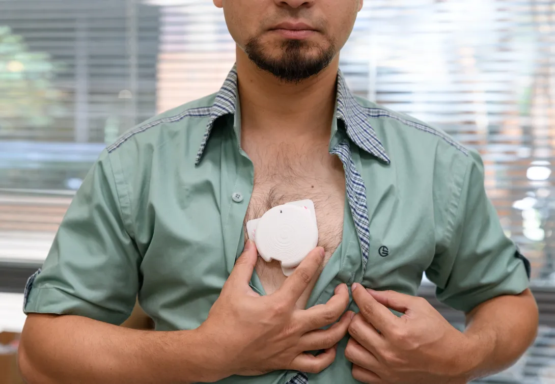 man baring chest an holding a patch against his skin
