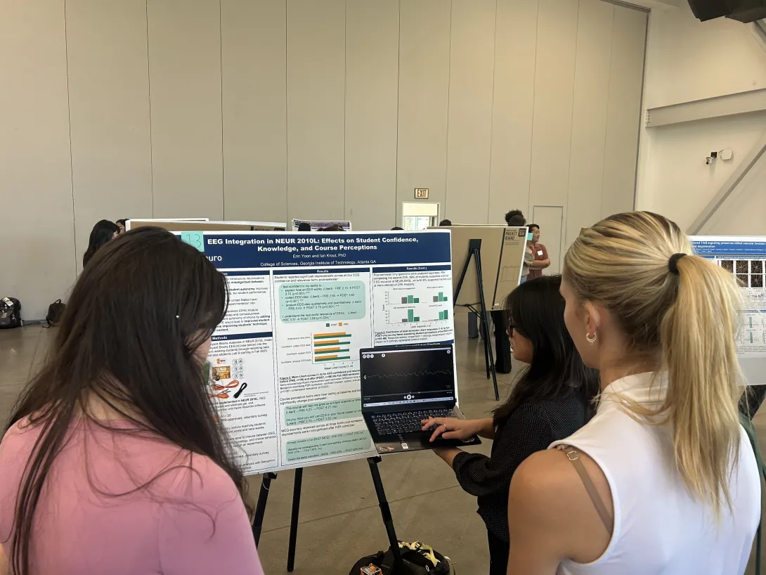A group of students is discussing a poster, and the presenter is giving an example during the first poster session. 