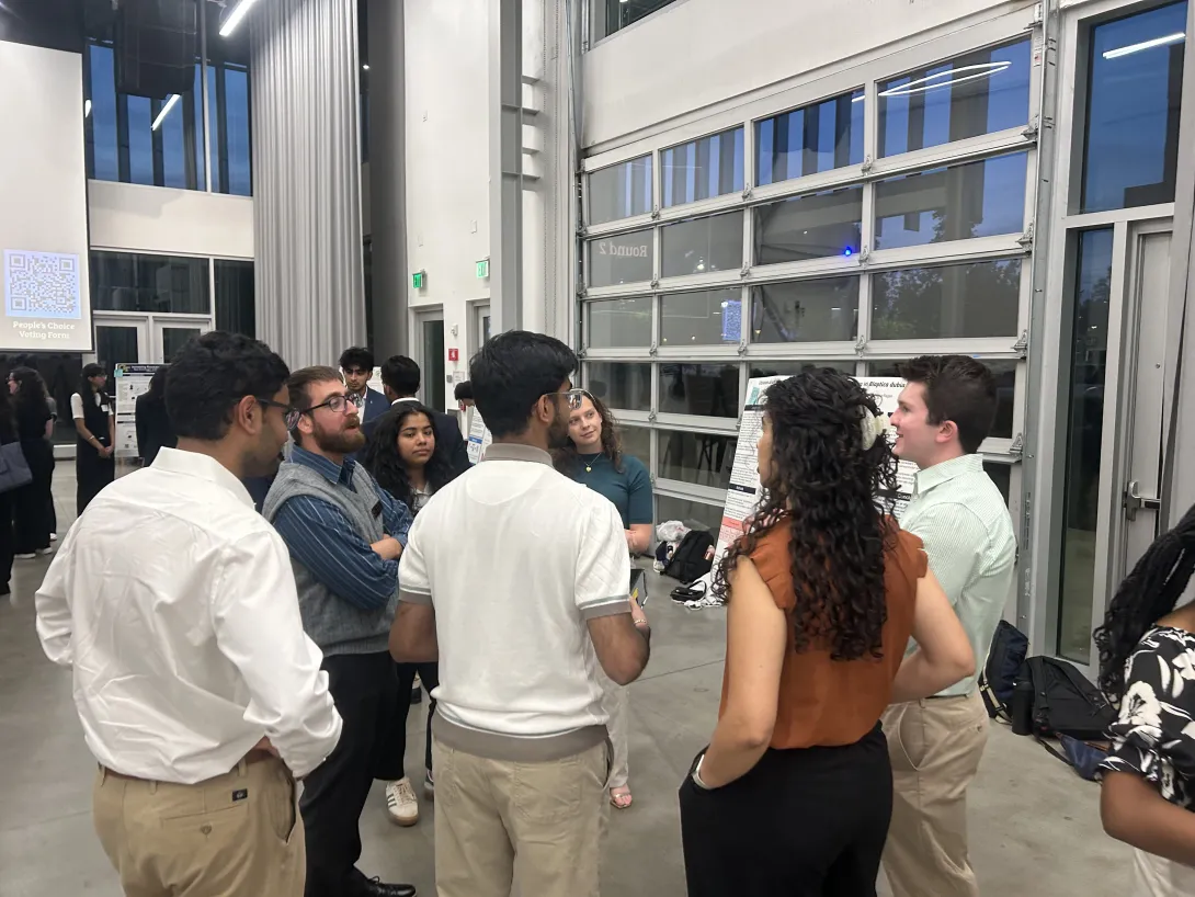A group of students and faculty is discussing a capstone poster during the second poster session. 