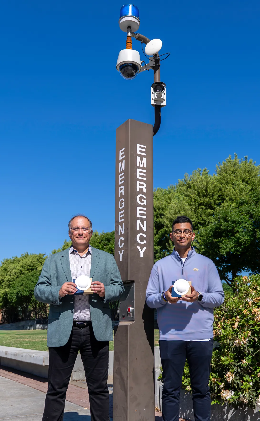 Shown near existing campus emergency infrastructure, the lens‑enabled backscatter device highlights how ultra‑low‑power wireless systems could be integrated directly into everyday infrastructure without relying on batteries or wired power.