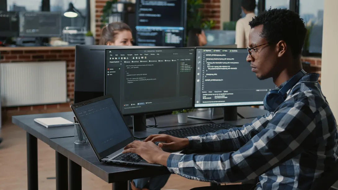 man sitting at computer doing programming. 