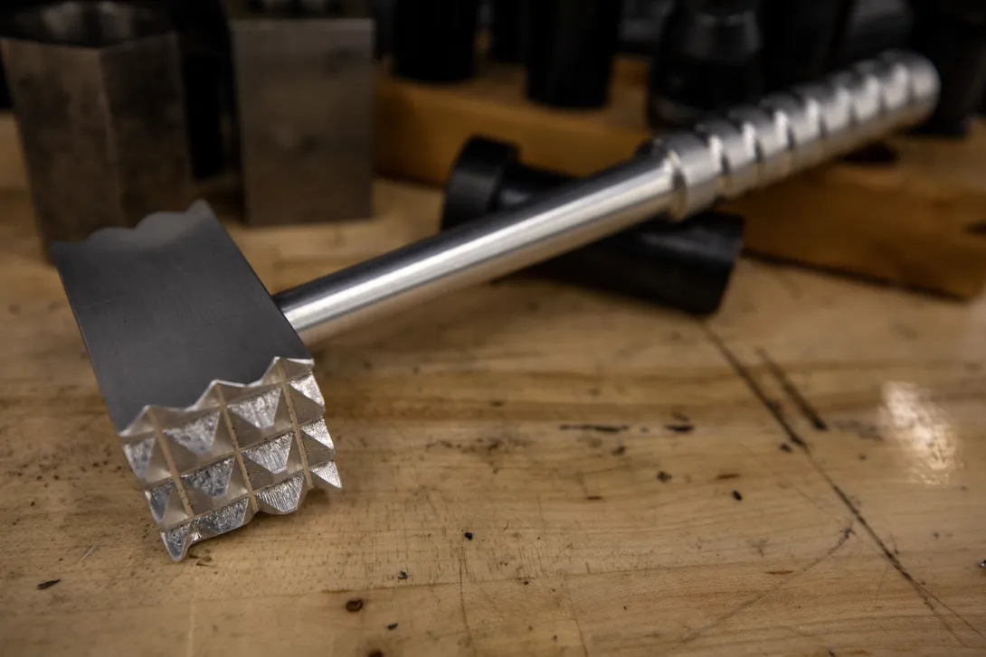 A metal meat tenderizer with a textured striking surface created by participants at a Georgia Tech workshop. 