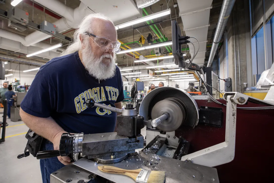 A participant at a Georgia Tech manufacturing workshop cuts metal on industrial equipment. 