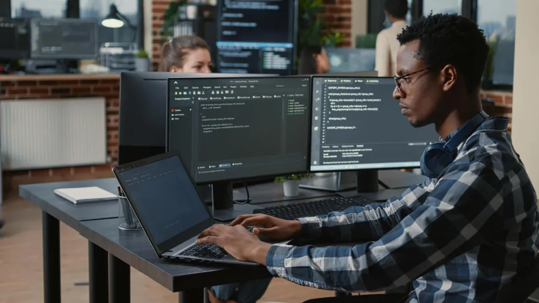 man sitting at computer doing programming. 