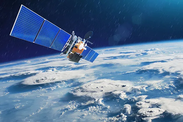 Satellite with large blue solar panels orbiting above Earth, showing cloud formations and the planet's curvature against a dark space background
