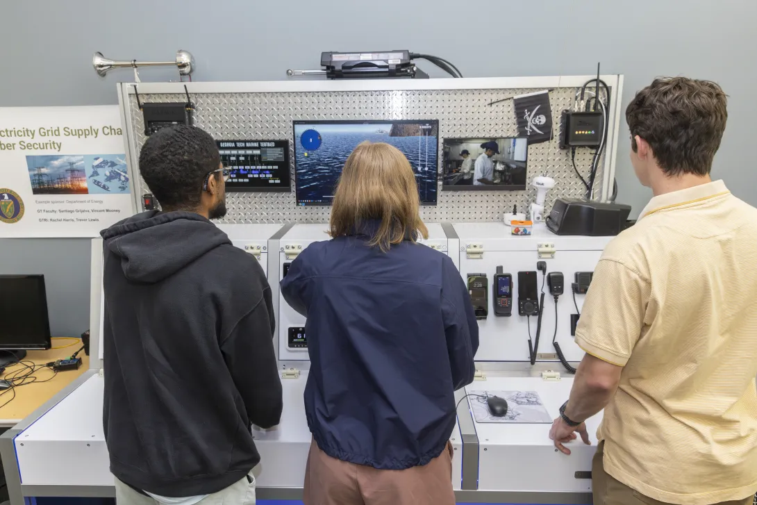 Three people working on a simulated ship in a lab