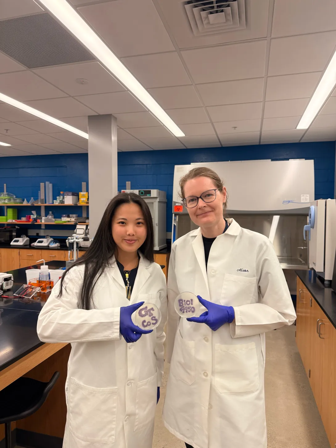Grace Tang (Left) and Alison Onstine (Right) holding bacteria plates that spell "BIOL 4590" (Credit: Tang and Onstine)