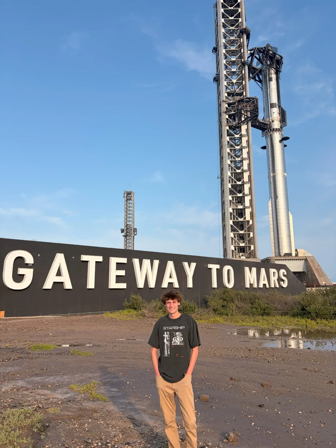 Guy Mastrion at SpaceX’s Starbase facility in Texas during his summer 2026 internship with the Starship Launch & Test team, pictured in front of the Starship launch tower and rocket.