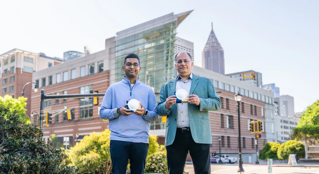 Professor Emmanouil “Manos” Tentzeris and Ph.D. student Marvin Joshi hold a lens‑enabled backscatter system that could support battery‑free wireless communication across future smart city infrastructure.