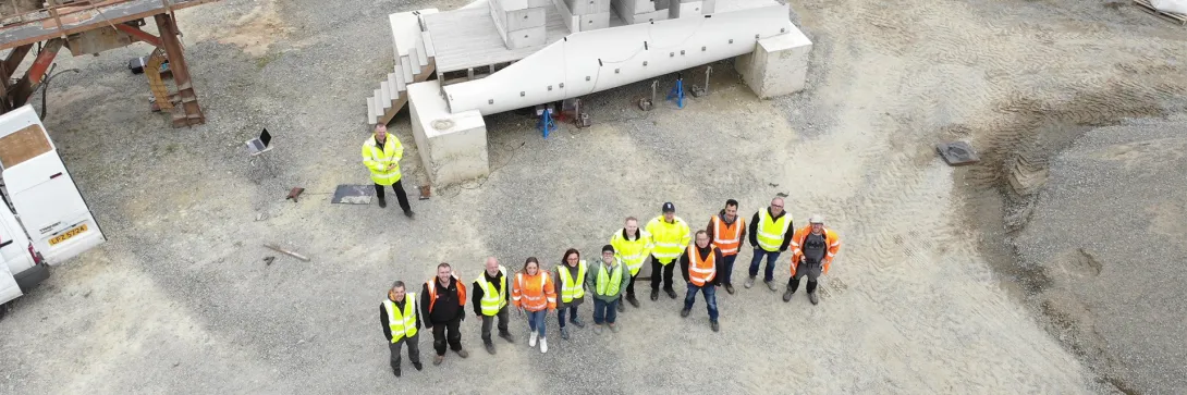 Overhead view of the Re-Wind crew doing structural testing on a decommissioned wind turbine blade bridge on an industrial lot.
